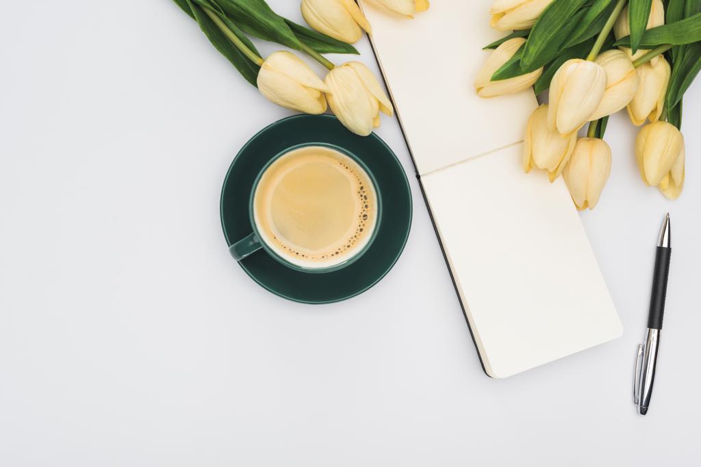 верхний вид тюльпанов, пустой блокнот с ручкой и свежий кофе изолированы на белом
 - Фото, изображение