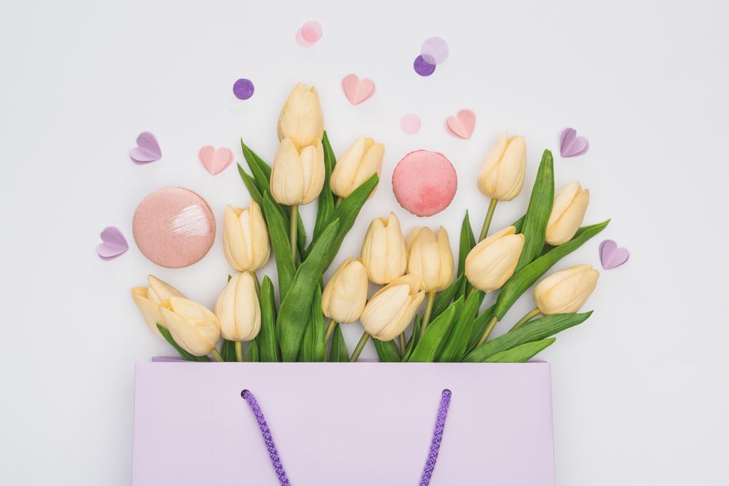 vista dall'alto di tulipani, amaretti rosa e cuori viola nella shopping bag isolati su bianco
 - Foto, immagini