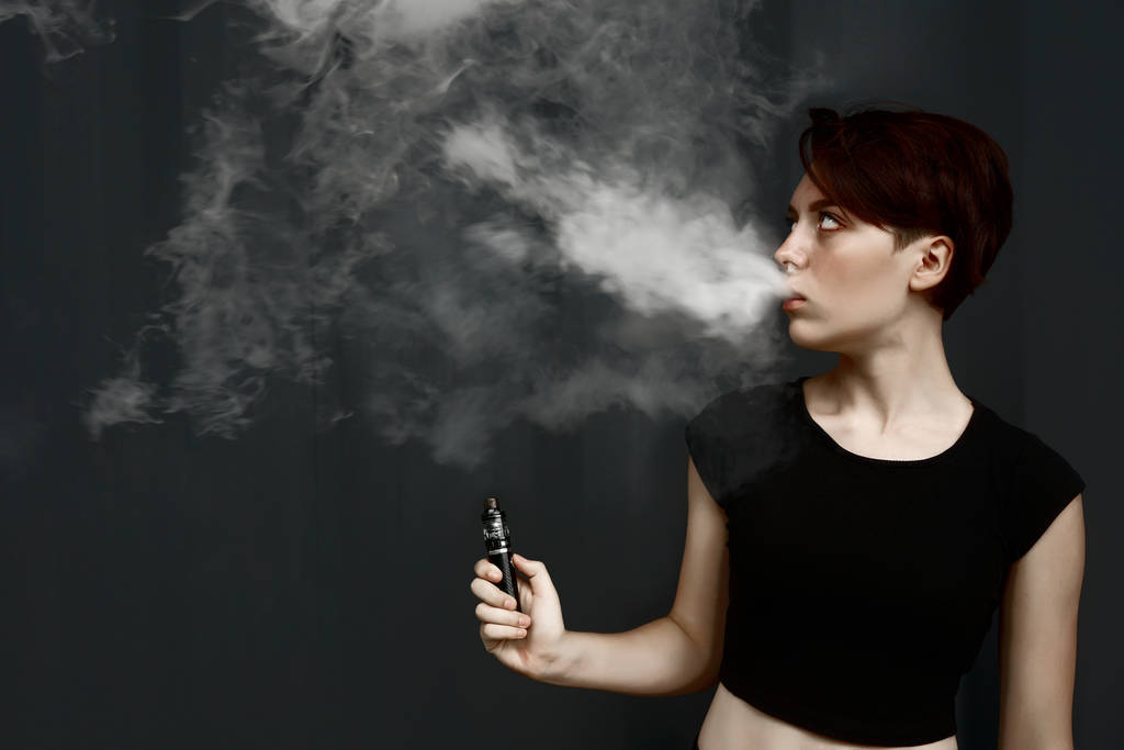 νεαρό κορίτσι καπνίζει ηλεκτρονικό τσιγάρο      - Φωτογραφία, εικόνα