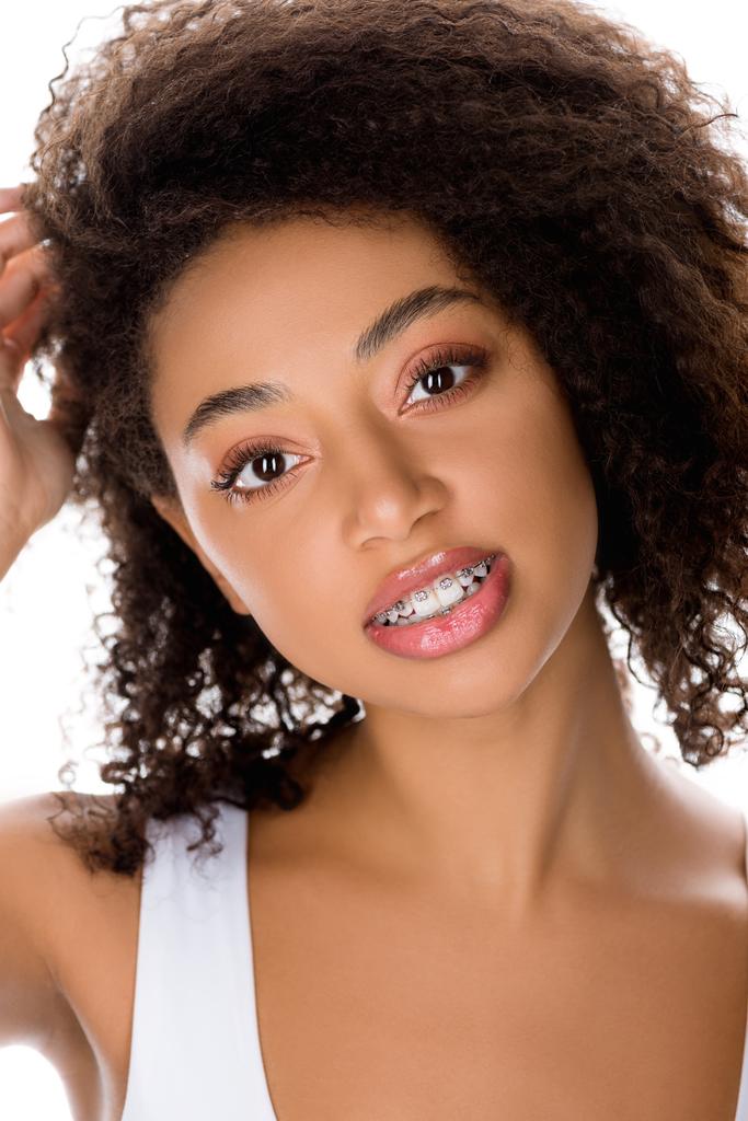 улыбающаяся африканская американка с зубными скобками, смотрящая в камеру, изолированная на белом
 - Фото, изображение