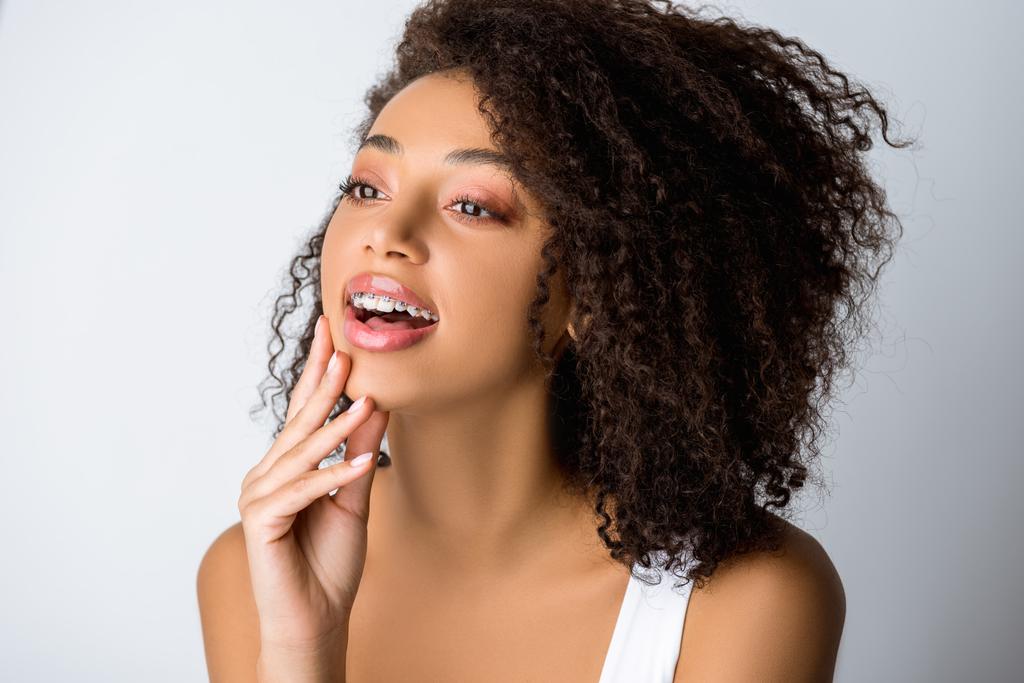 veselá africká americká dívka se zubními rovnátky, izolovaná na šedé - Fotografie, Obrázek