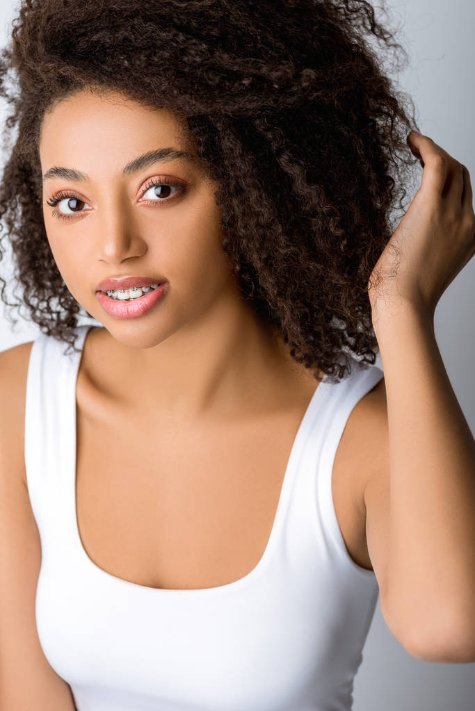 ελκυστική Αφροαμερικανή με οδοντικά σιδεράκια, απομονωμένη σε γκρι - Φωτογραφία, εικόνα