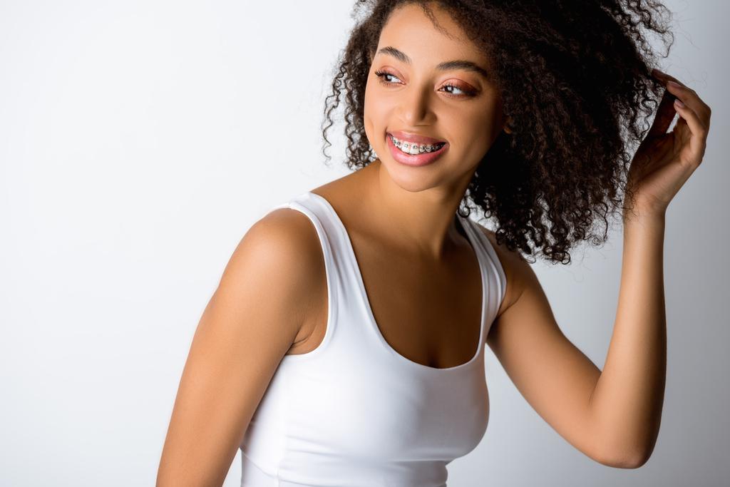feliz rizado chica afroamericana con frenos dentales, aislado en gris
 - Foto, imagen