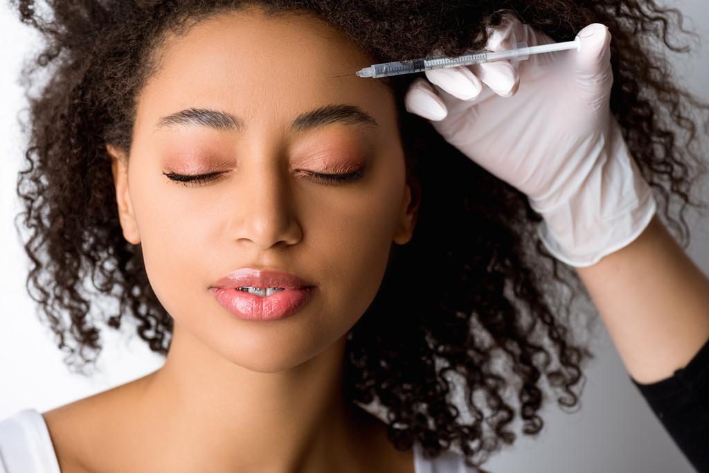 attractive african american woman making beauty injection, isolated on grey - Photo, Image