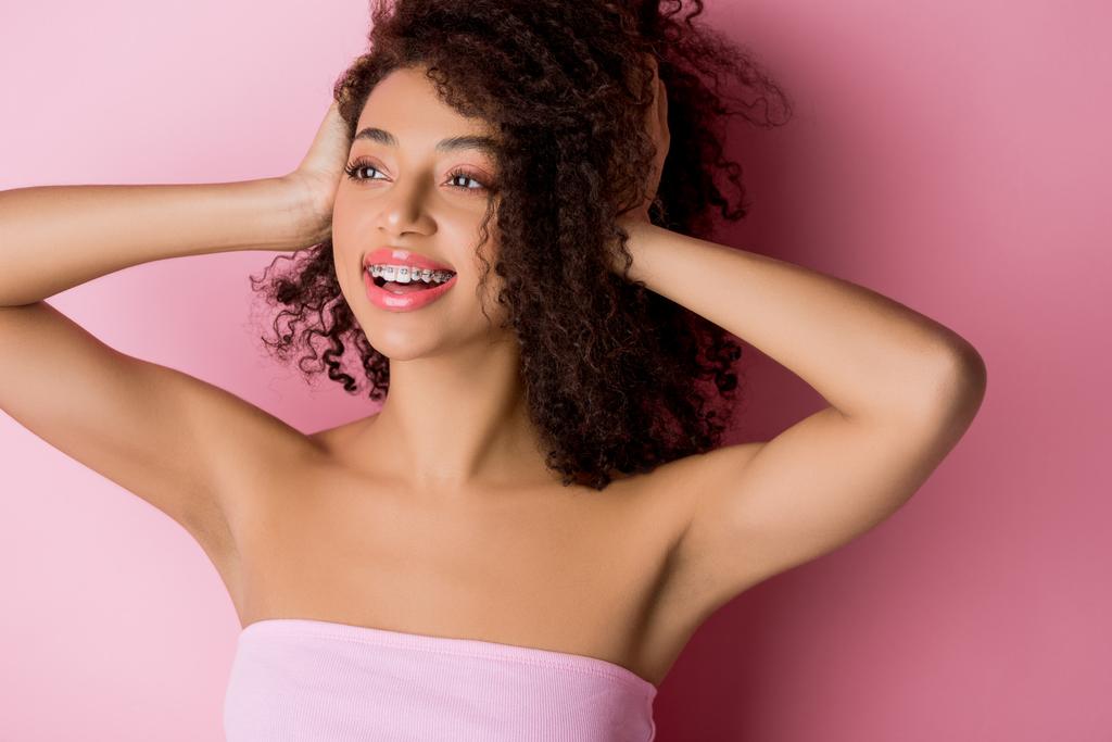 hermosa chica afroamericana positiva con frenos dentales en rosa
 - Foto, imagen