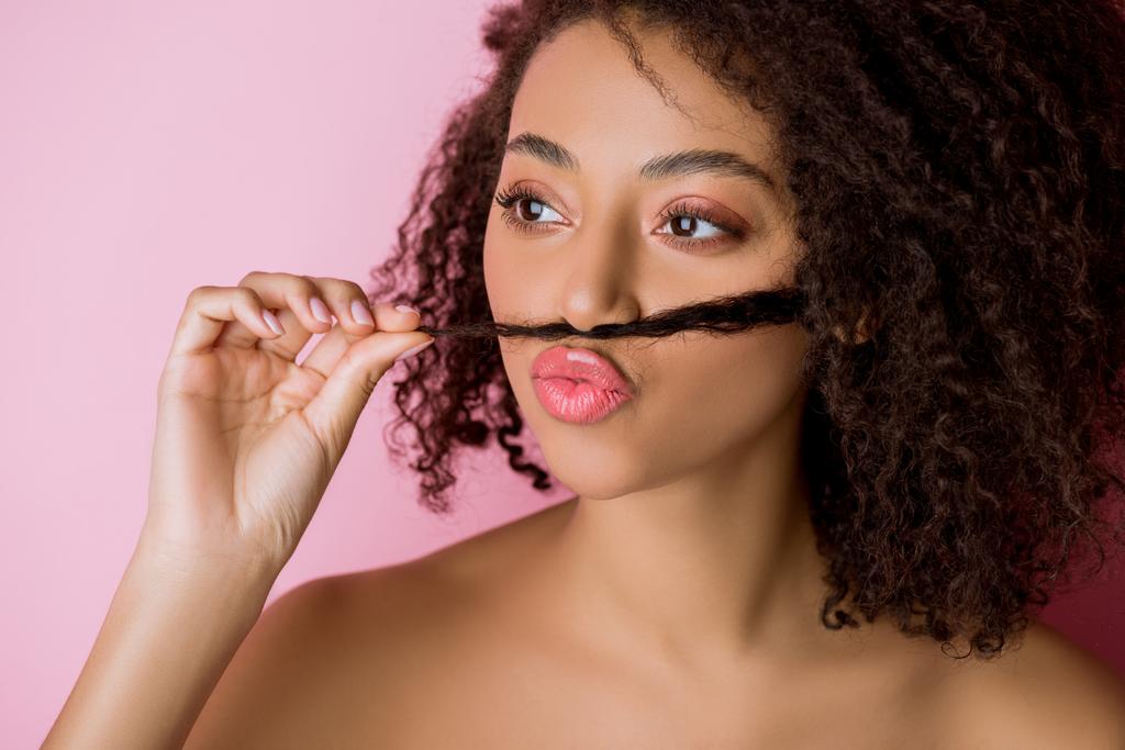 portrait of funny african american girl making fake mustache from hair, isolated on pink - Photo, Image