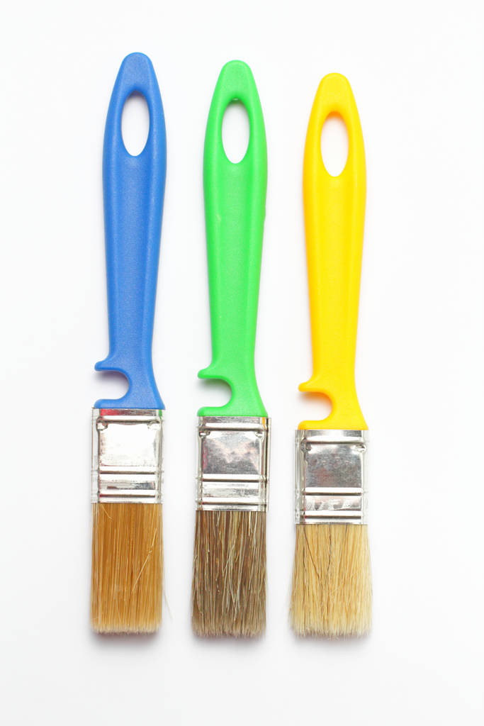 Tre pennelli con manico colorato su sfondo bianco primo piano, posa piatta
. - Foto, immagini