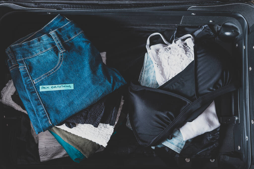 αποσκευές με σωρό ρούχα και συσκευασία Όλα ετικέτα στο - Φωτογραφία, εικόνα