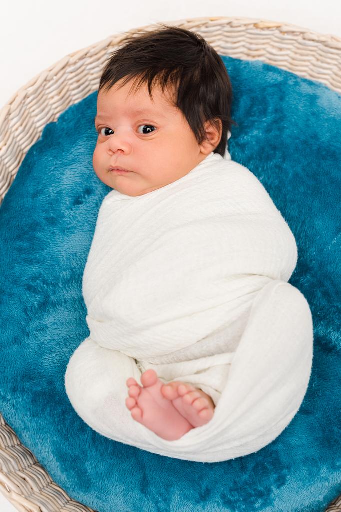 vista superior do bebê bonito recém-nascido misto envolto em cobertor deitado em cesta isolada no branco
  - Foto, Imagem