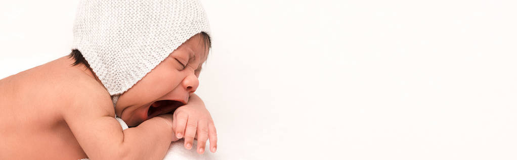 colpo panoramico di adorabile razza mista bambino in maglia cappello sbadigliare isolato su bianco
  - Foto, immagini