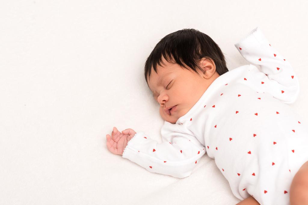 overhead view of bi-racial newborn in baby romper sleeping isolated on white  - Photo, Image