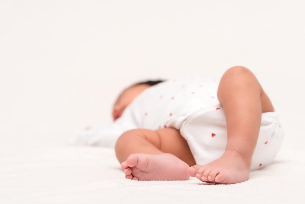 foyer sélectif de nouveau-né mignon dans la barboteuse et chaussettes de bébé couché sur blanc
  - Photo, image