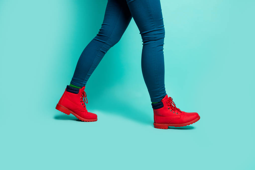 Περικοπή closeup προφίλ φωτογραφία του ταιριάζει κυρία πόδια ισχία με τα πόδια κάτω στο εξωτερικό δρόμο ξένη χώρα φορούν κομψό κόκκινο παντελόνι παπούτσια απομονωμένο φόντο teal χρώμα - Φωτογραφία, εικόνα