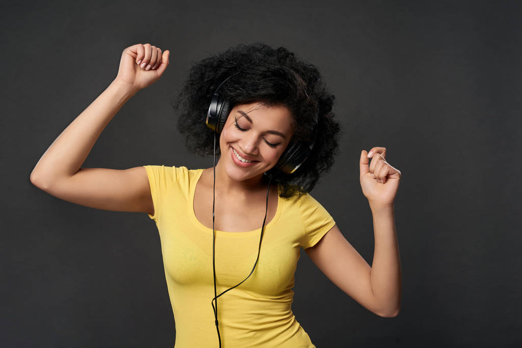 Щаслива жінка слухає музику в навушниках і танцює із закритими очима
 - Фото, зображення