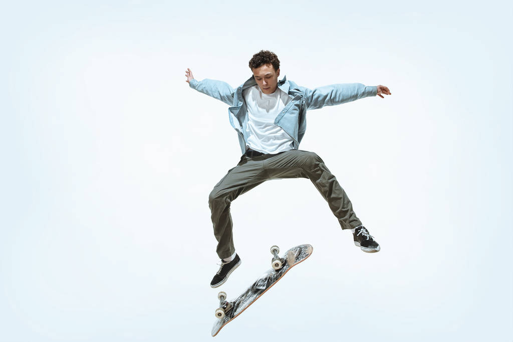 Kaukasische jonge skateboarder rijden geïsoleerd op een witte achtergrond - Foto, afbeelding