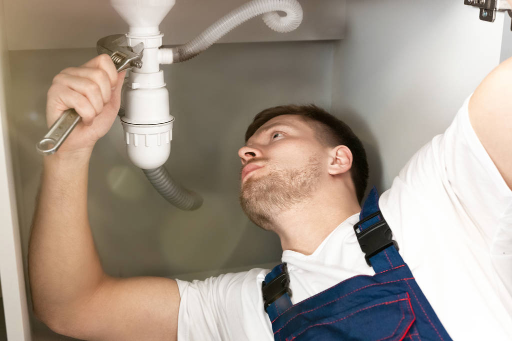 mies putkimies yhtenäinen vahvistamisesta pesuallas putki keittiössä säädettävällä avaimella kädessään näyttää keskittynyt ammatillinen LVI korjauspalvelu
 - Valokuva, kuva