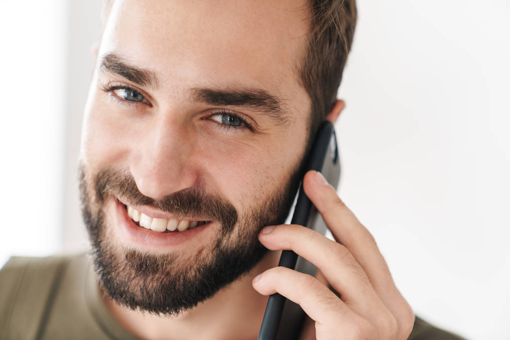 Εικόνα από κοντινό πλάνο του καυκάσιου ευτυχισμένου άντρα να μιλάει στο κινητό και να χαμογελάει - Φωτογραφία, εικόνα