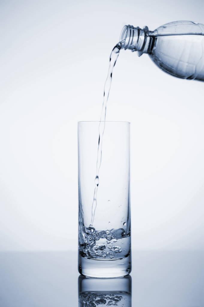 L'acqua minerale limpida è versata in un bicchiere con ghiaccio
.  - Foto, immagini