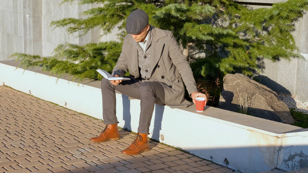 Молодой мужчина читает книгу на улице
 - Фото, изображение