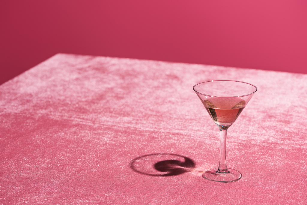 bebida alcoólica em vidro em veludo pano rosa isolado em rosa, conceito feminino
 - Foto, Imagem