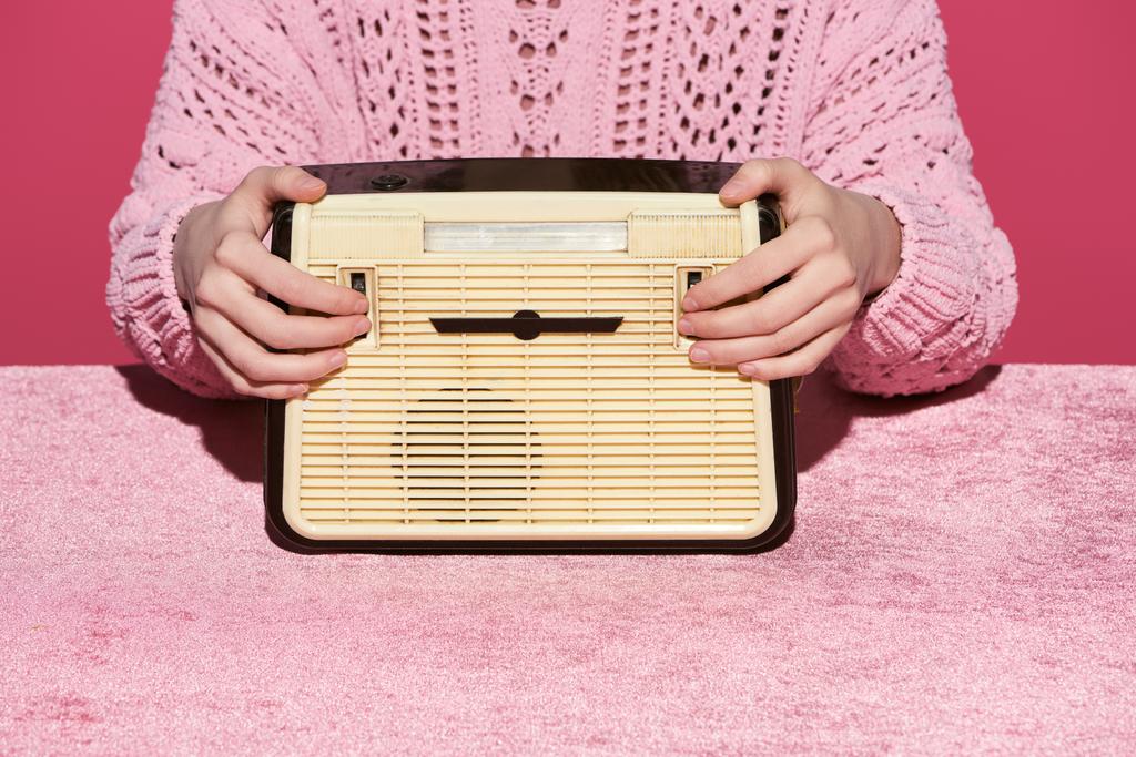 bijgesneden beeld van vrouw met vintage radio op velours doek geïsoleerd op roze, meisjesachtige concept  - Foto, afbeelding