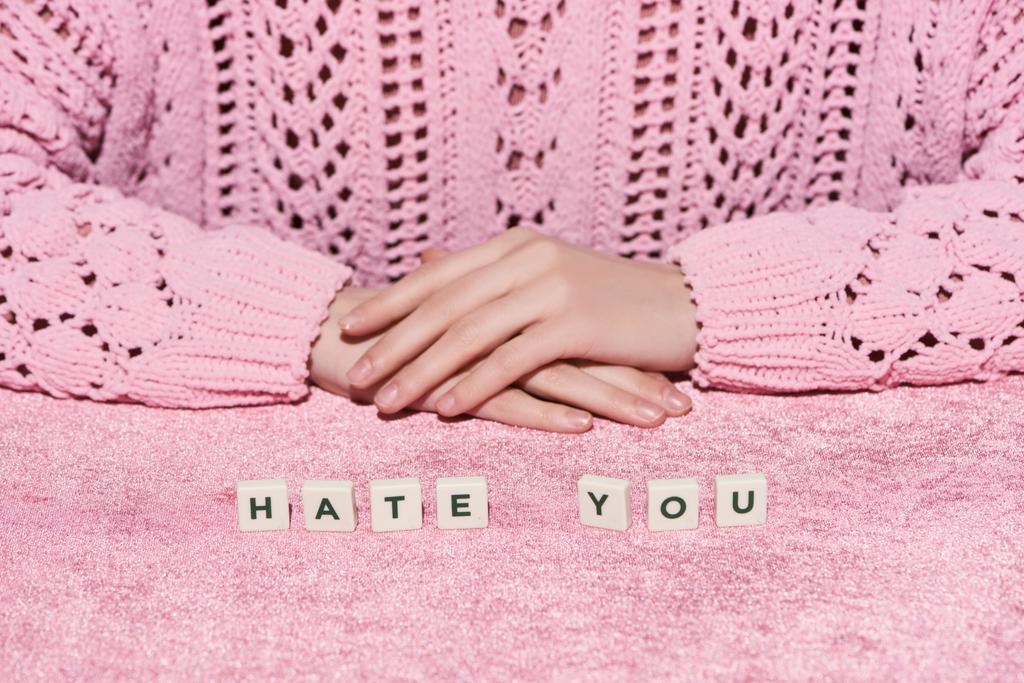 ostříhaný pohled na ženu ve svetru blízko nenávisti, nápis na růžovém sametu, dívčí koncept  - Fotografie, Obrázek