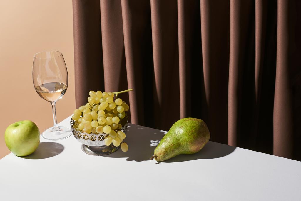 natura morta classica con vino bianco e frutta sul tavolo vicino alla tenda isolata sul beige
 - Foto, immagini