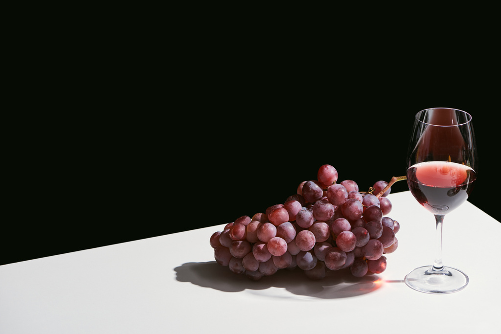 klasické zátiší s hroznem a červeným vínem na bílém stole izolované na černé - Fotografie, Obrázek