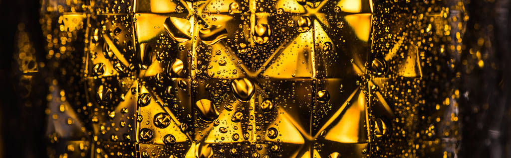 vista de cerca de vidrio facetado geométrico con iluminación amarilla en plano oscuro y panorámico
 - Foto, imagen