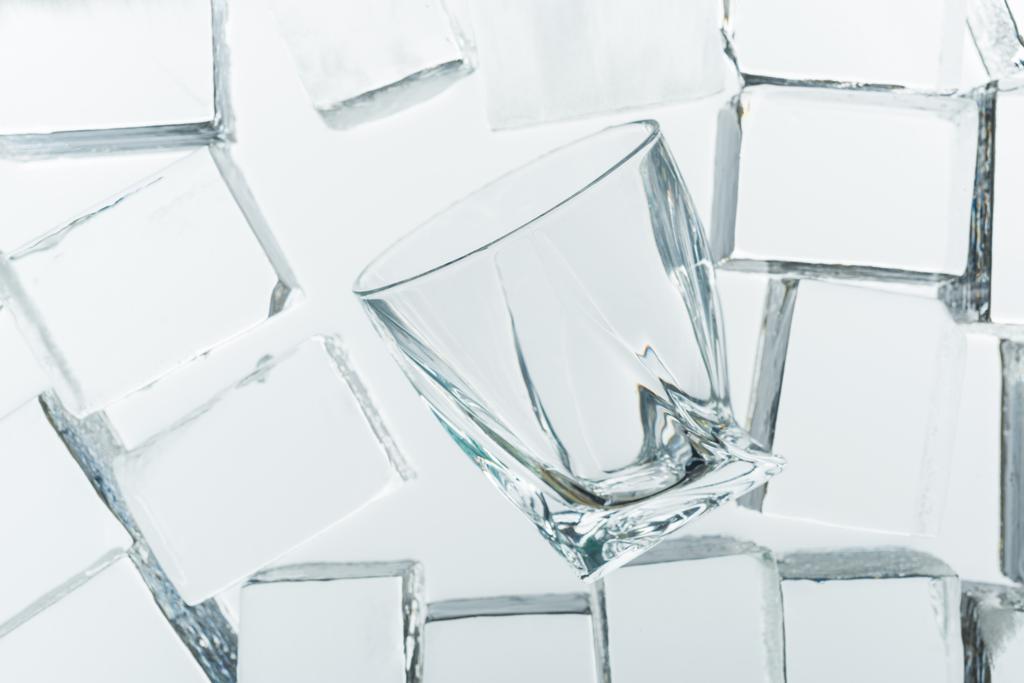 Draufsicht auf transparente quadratische Eiswürfel und leeres Glas auf Spiegel - Foto, Bild