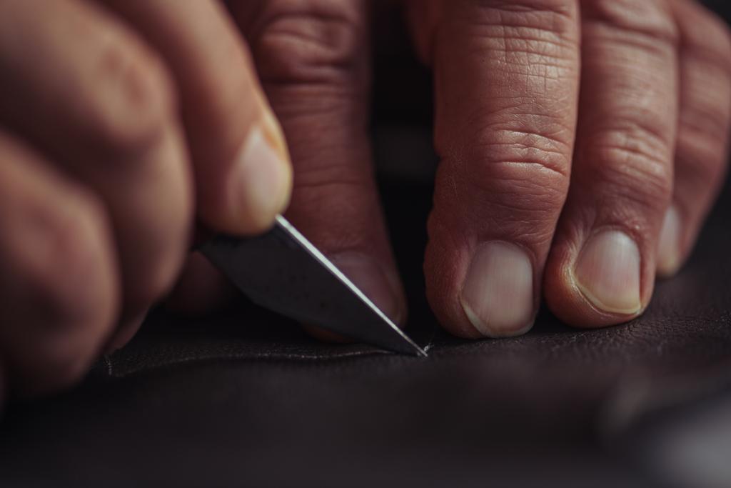 vista recortada de zapatero de corte de cuero genuino con cuchillo
 - Foto, Imagen