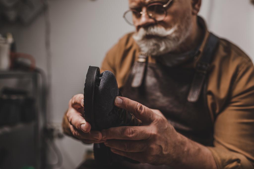 selective focus of senior cobbler repairing shoe in workshop - Photo, Image