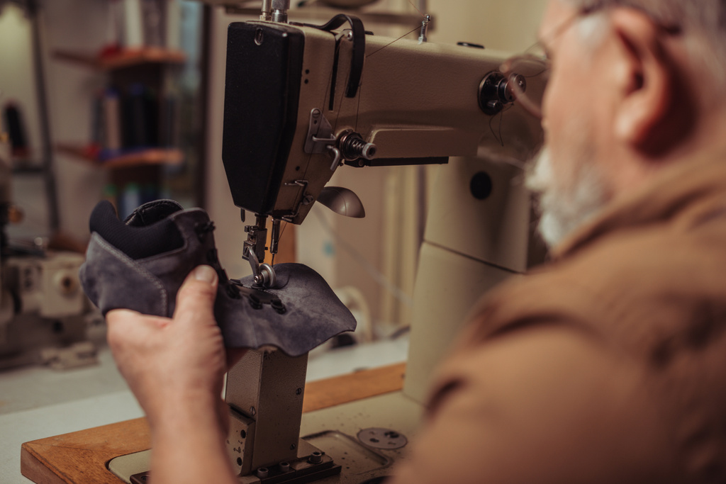 επιλεκτική εστίαση του τσαγκάρη ράψιμο μέρος του suede παπούτσι στη ραπτομηχανή - Φωτογραφία, εικόνα