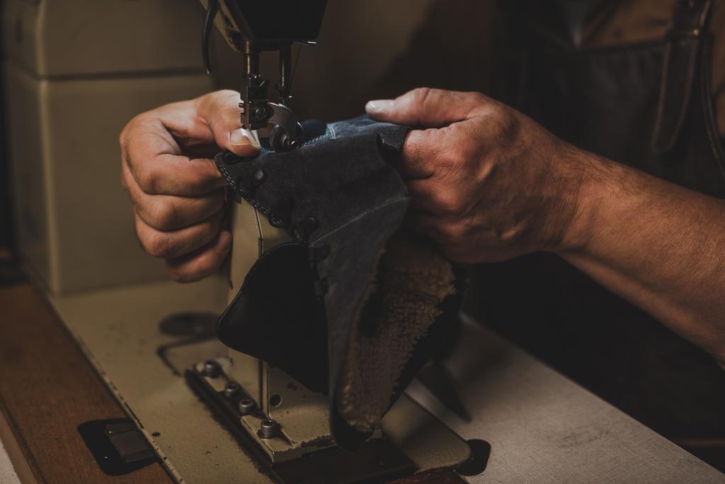 Ausgeschnittene Ansicht eines Schusters, der einen Teil des Lederschuhs an der Nähmaschine näht - Foto, Bild