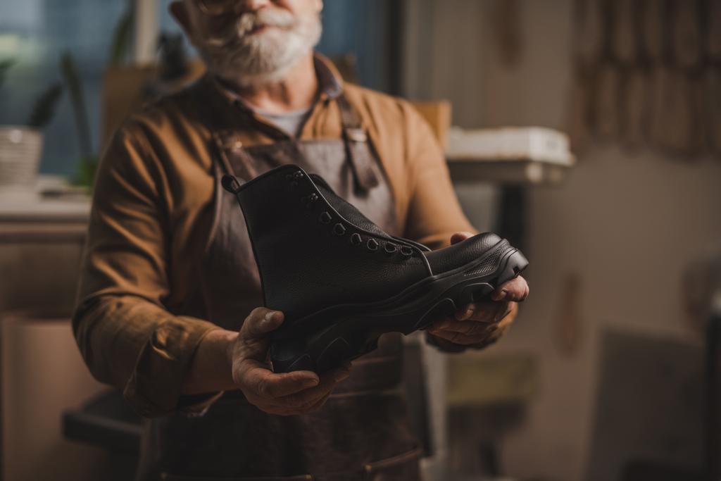 foco seletivo de sapateiro mostrando bota de couro artesanal na oficina
 - Foto, Imagem