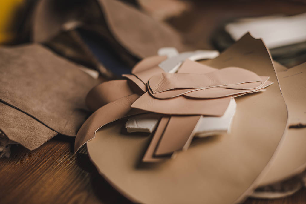 селективный фокус кожаных деталей на деревянном столе в мастерской
 - Фото, изображение