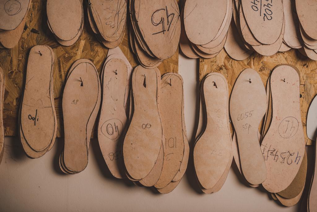 plantillas de calzado de diferentes tamaños colgadas en la pared en el taller
 - Foto, Imagen