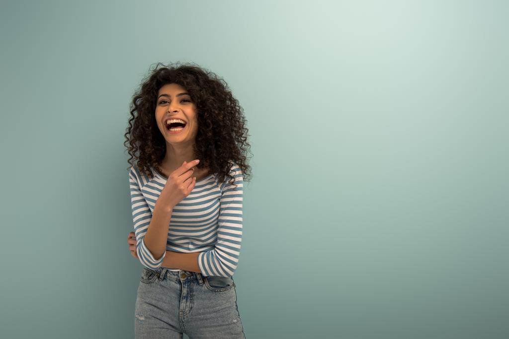 eccitato bi-razziale ragazza ridendo mentre punta con il dito su sfondo grigio
 - Foto, immagini