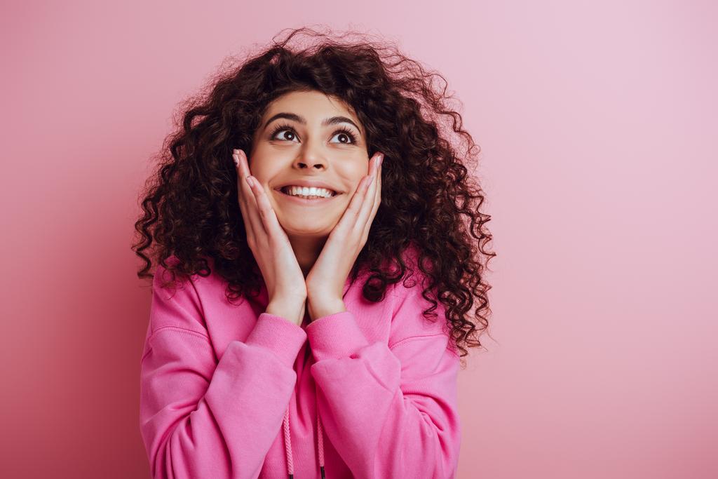 boldog bi-rasszista lány megható arc és felnézett rózsaszín háttér - Fotó, kép