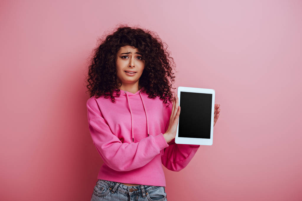 chica bi-racial disgustado mostrando tableta digital con pantalla en blanco sobre fondo rosa
 - Foto, imagen
