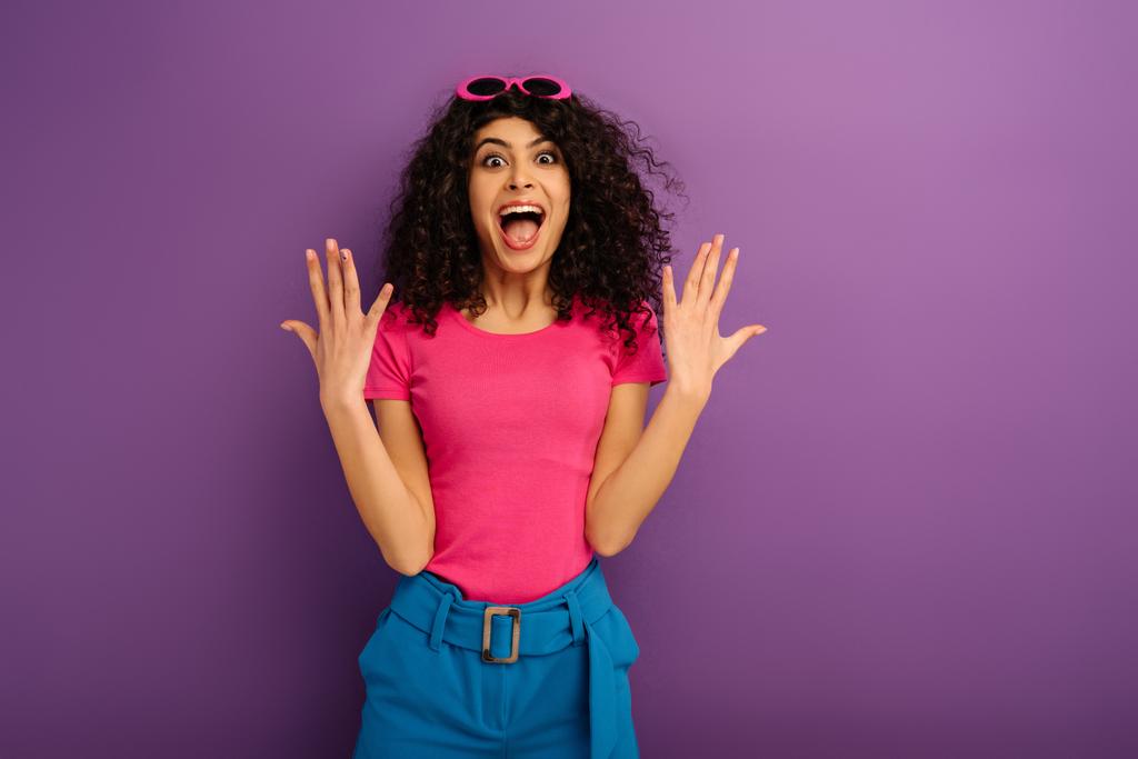 excited bi-racial girl showing wow gesture while looking at camera on purple background - 写真・画像