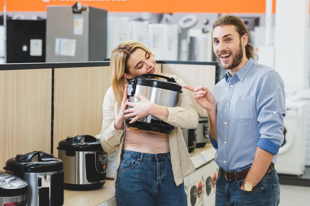 consultant souriant pointant du doigt la femme avec cuisinière lente dans le magasin d'appareils ménagers
  - Photo, image