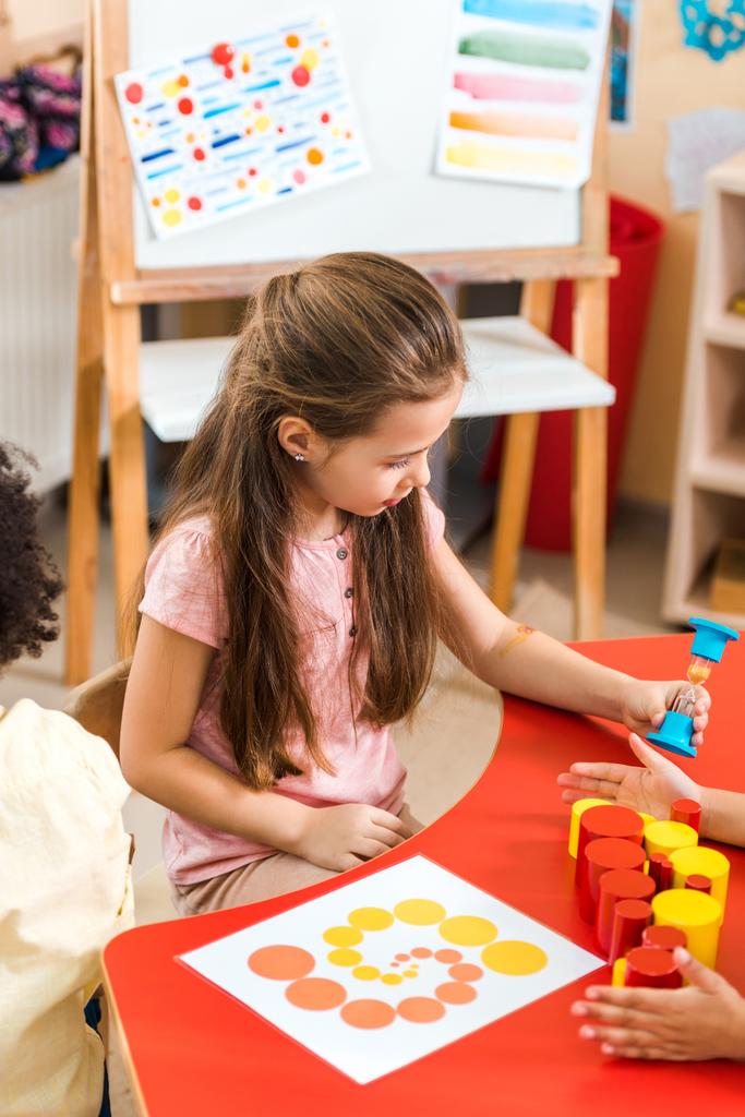 Děti hrající si s přesýpacími hodinami a vzdělávací hra na stole ve škole Montessori - Fotografie, Obrázek