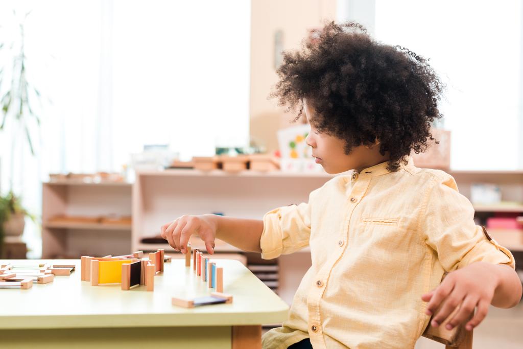 Sivunäkymä afrikkalainen amerikkalainen lapsi pelaa peliä pöydässä Montessori koulussa
 - Valokuva, kuva