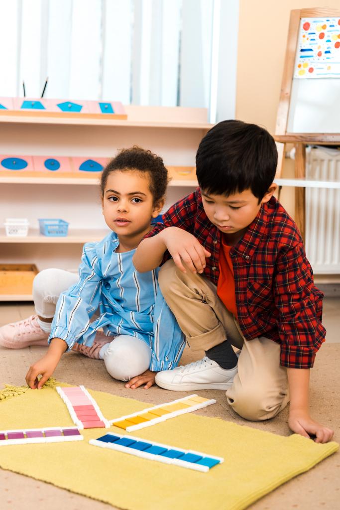 Bambini che giocano con gioco colorato su tappeto in classe montessori
 - Foto, immagini