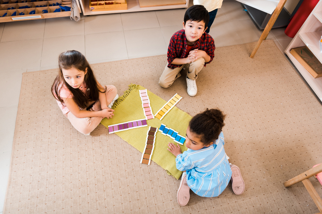 モンテッソーリ校の床に遊ぶ子供たちの高い角度の眺め - 写真・画像