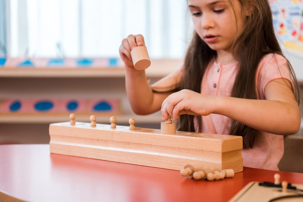 Kind spielt hölzernes Lernspiel in Montessori-Schule - Foto, Bild