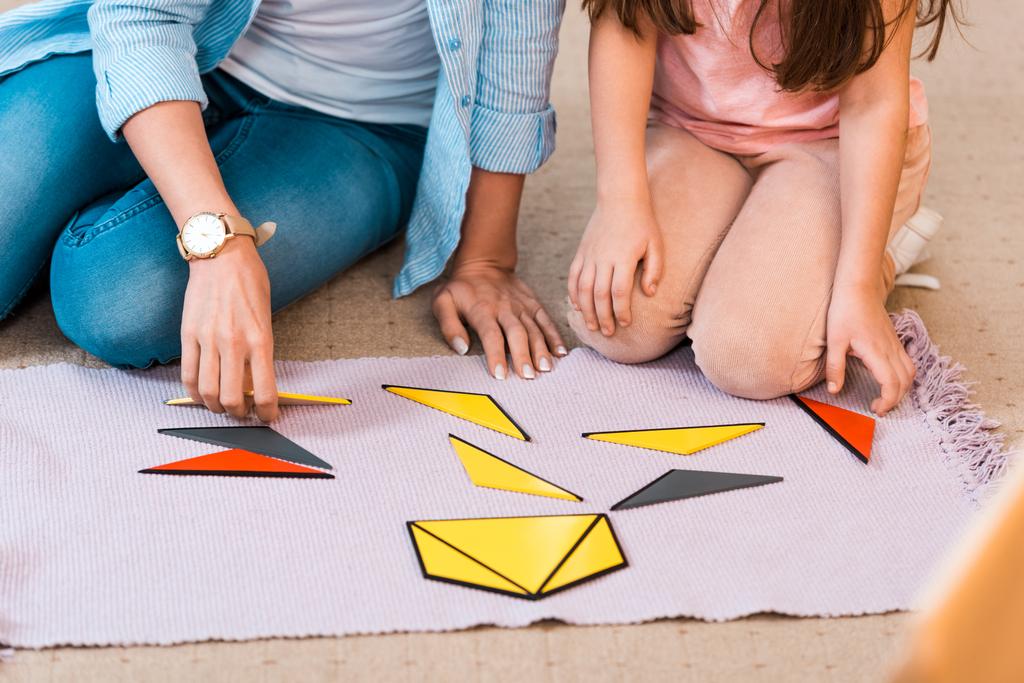 Обрезанный вид детей и учителей, играющих в образовательные игры на полу в классе Монтессори
 - Фото, изображение