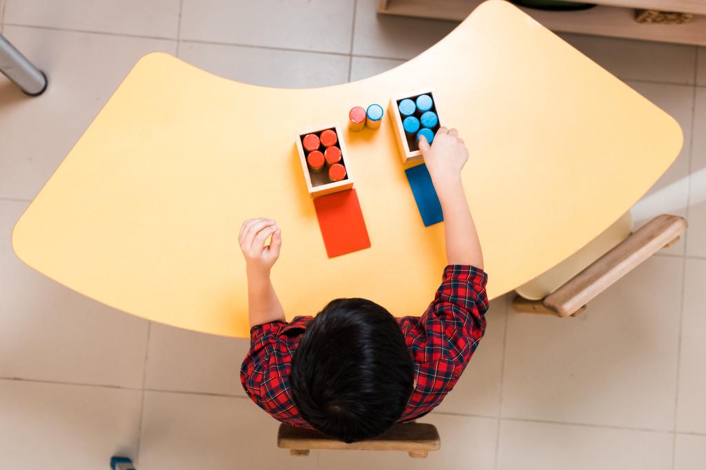 Pohled shora na dětskou skládací barevnou hru na stole během lekce ve škole Montessori  - Fotografie, Obrázek