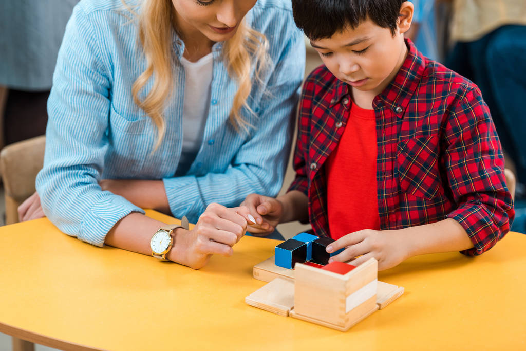 asiatisches Kind spielt Bausteine von Lehrer in Montessori-Klasse  - Foto, Bild